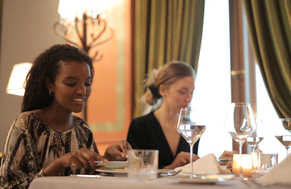 Two women enjoying a refined dining experience in a stylish restaurant setting.