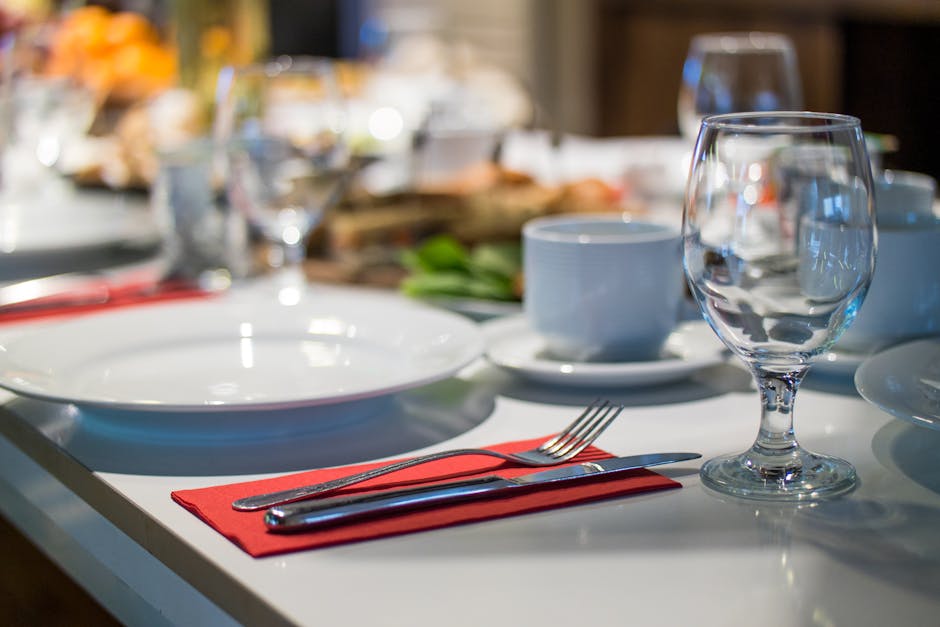 Close-up of an elegant dining table set with glassware, silverware, and red napkins in a restaurant setting