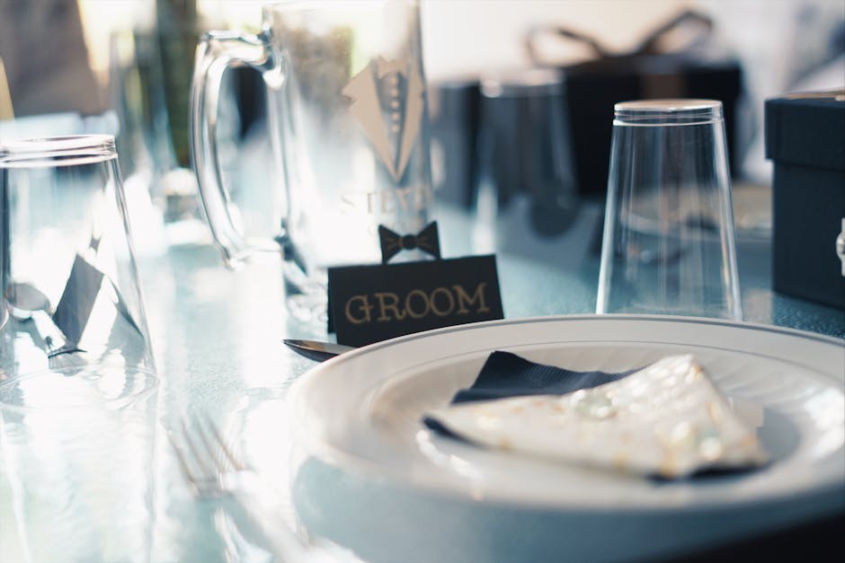 A sophisticated wedding table setting featuring a groom card with elegant glassware and plates